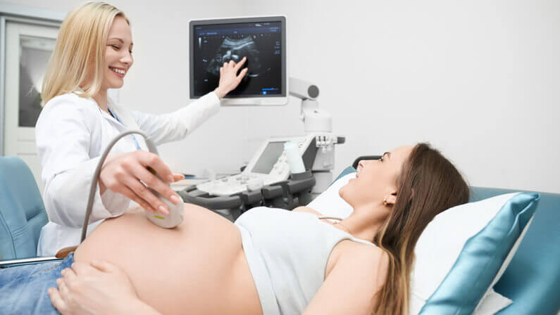 doctor performs an ultrasound to the pregnant woman