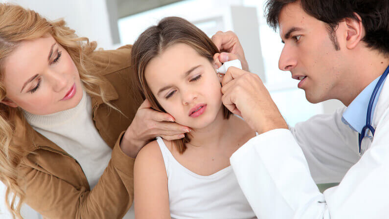 doctor checking little girl for a ear infection with her mother