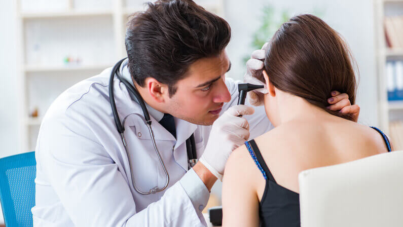 doctor checking women patient for a possible middle ear infection