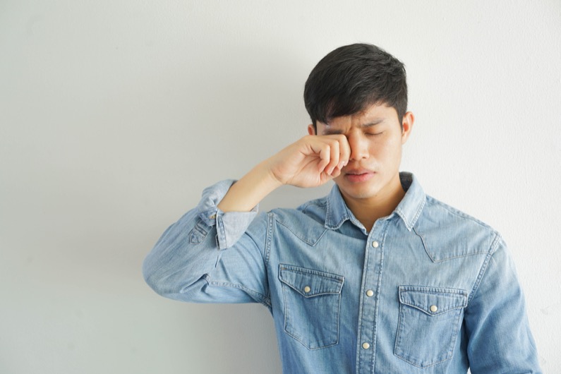 close up young man using hand to rubbing eyes after feeling itchy for conjunctivitis healthcare concept