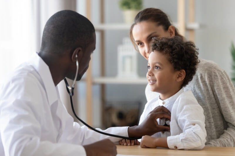 African American Male Pediatrician With Stethoscope Listening To Child's Lung