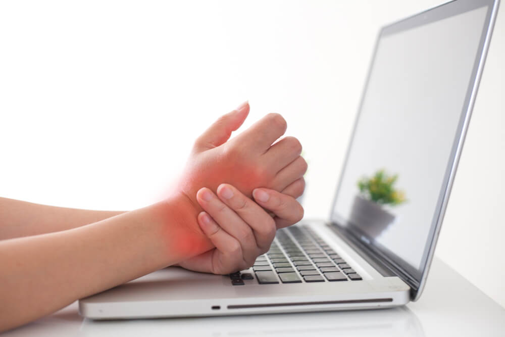 Woman holding her wrist pain from using computer.,Hand pain