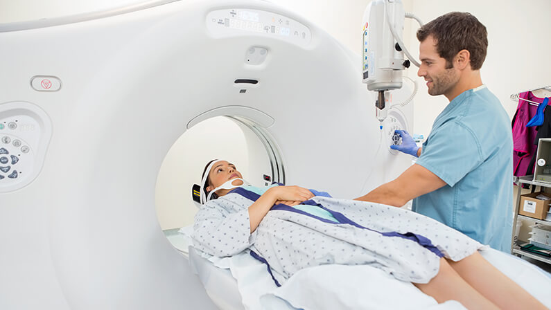 Male nurse preparing young patient for CT scan test in hospital room